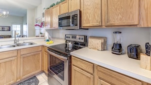 A modern kitchen with wooden cabinets, stainless steel appliances, a microwave, a stove, a toaster, and a blender. - Unit 15 | 3BR Home | 2 Mi to Disney | Pet Friendly | Heated Pool | Gated (Kissimmee)