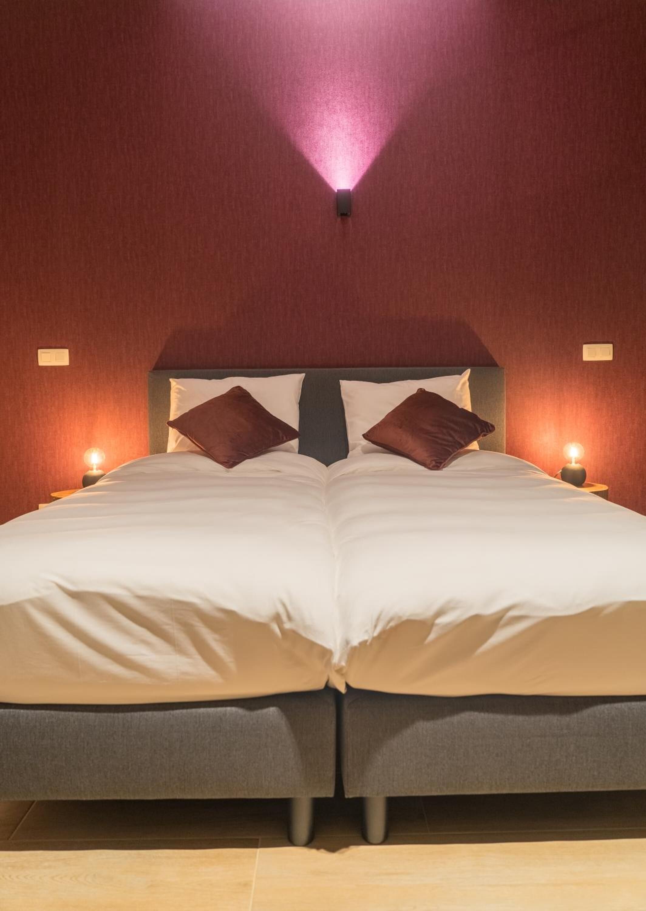 A double bed with a headboard, two bedside lamps, and a wall-mounted light fixture.