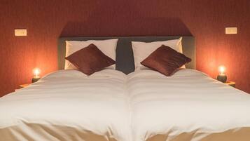 Een tweepersoonsbed met hoofdeinde, twee bedlampjes en een wandlamp.