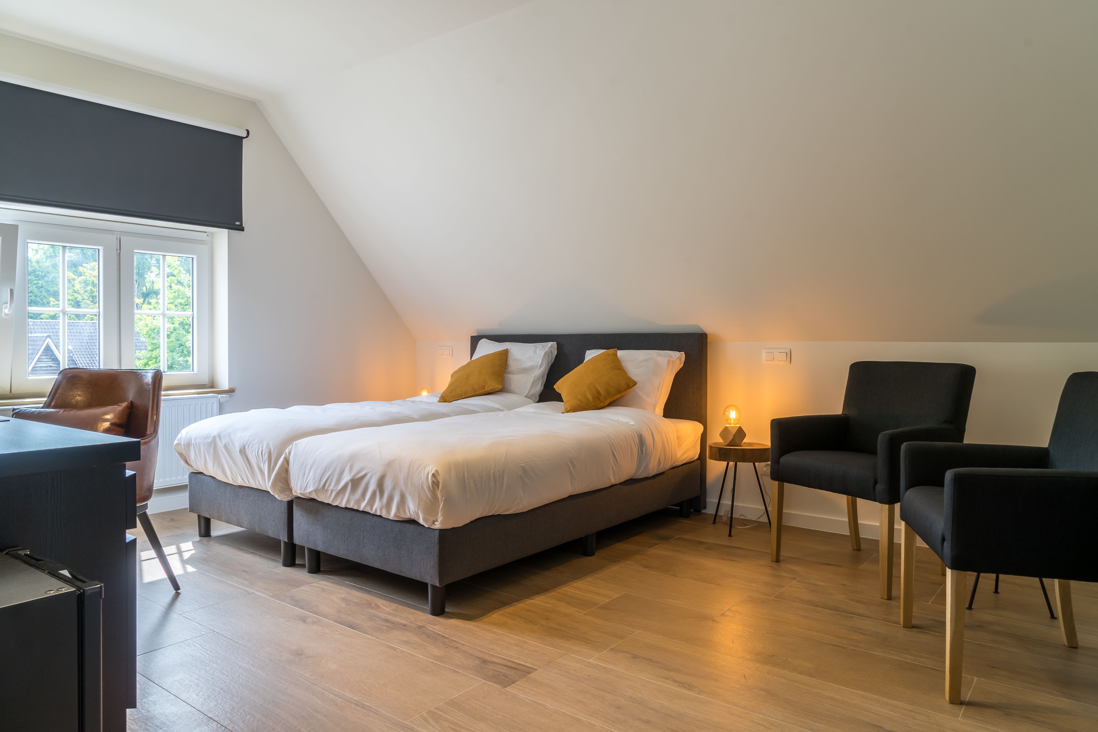 A modern bedroom with a large bed, a desk, and two chairs.