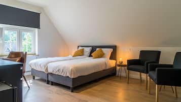 A modern bedroom with a large bed, a desk, and two chairs.