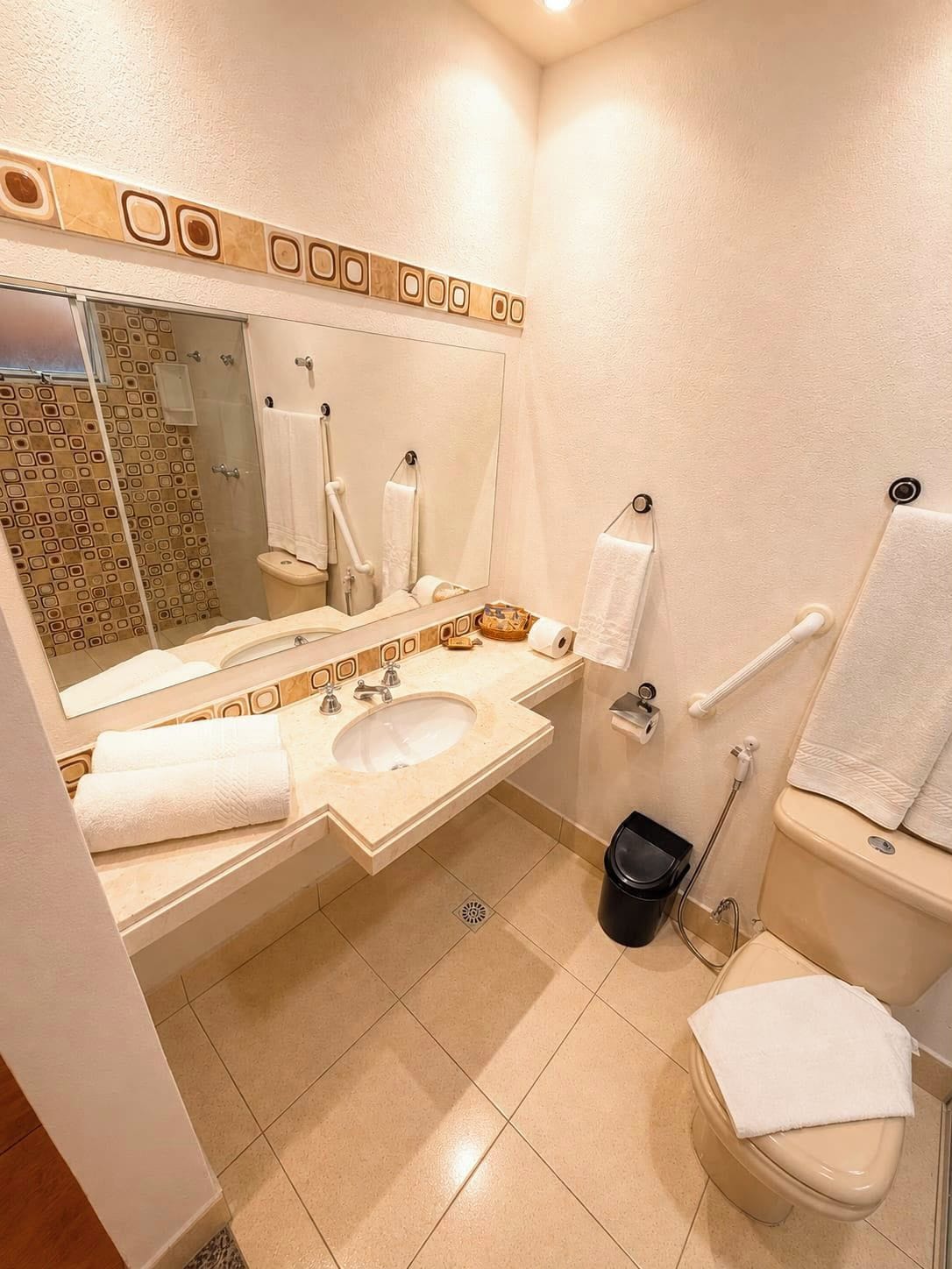 Un baño con lavamanos, espejo, inodoro y zona de ducha.