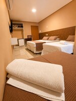 Habitación de hotel con dos camas, un armario, un escritorio y un refrigerador.