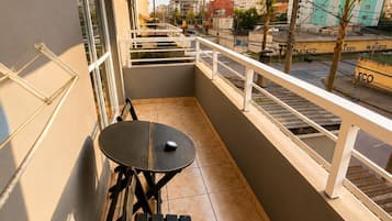 Un balcon avec une table et des chaises, une balustrade et une vue sur le paysage urbain.