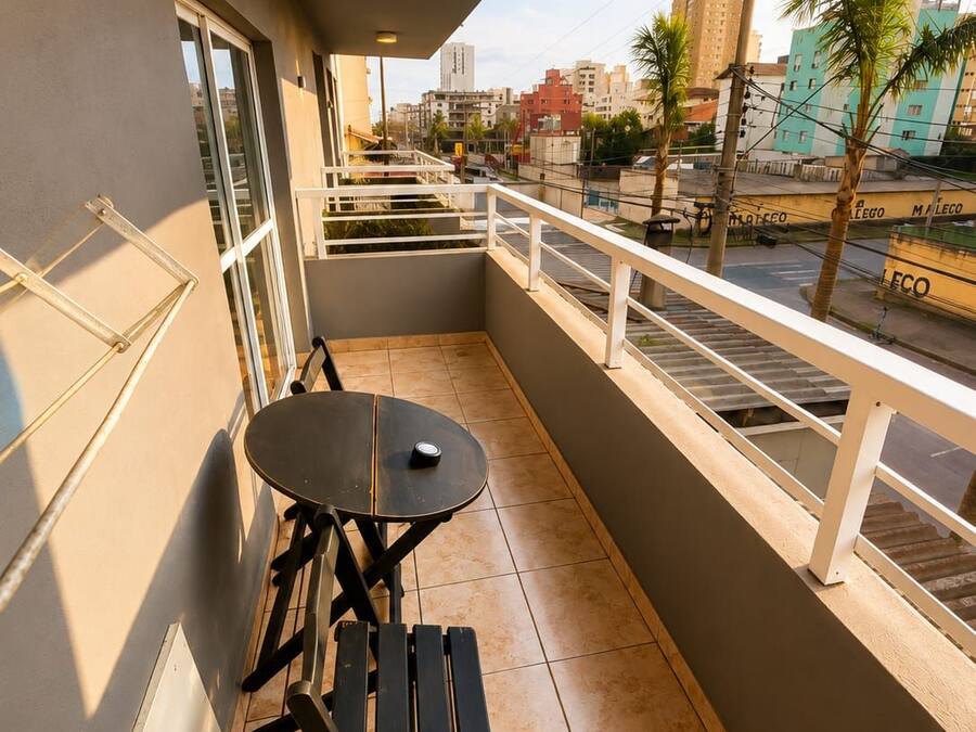 Un balcon avec une table et des chaises, une balustrade et une vue sur le paysage urbain.