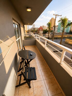 A balcony with a table and chairs, a railing, and a view of the cityscape.