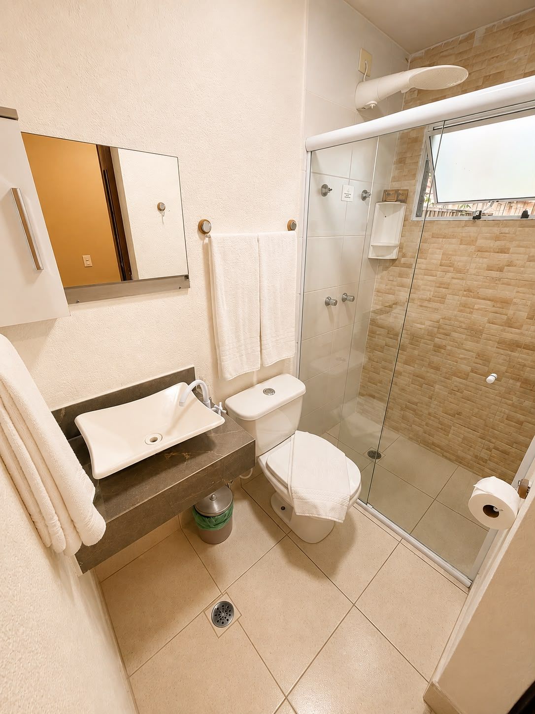 A bathroom with a shower, toilet, sink, and a mirror.