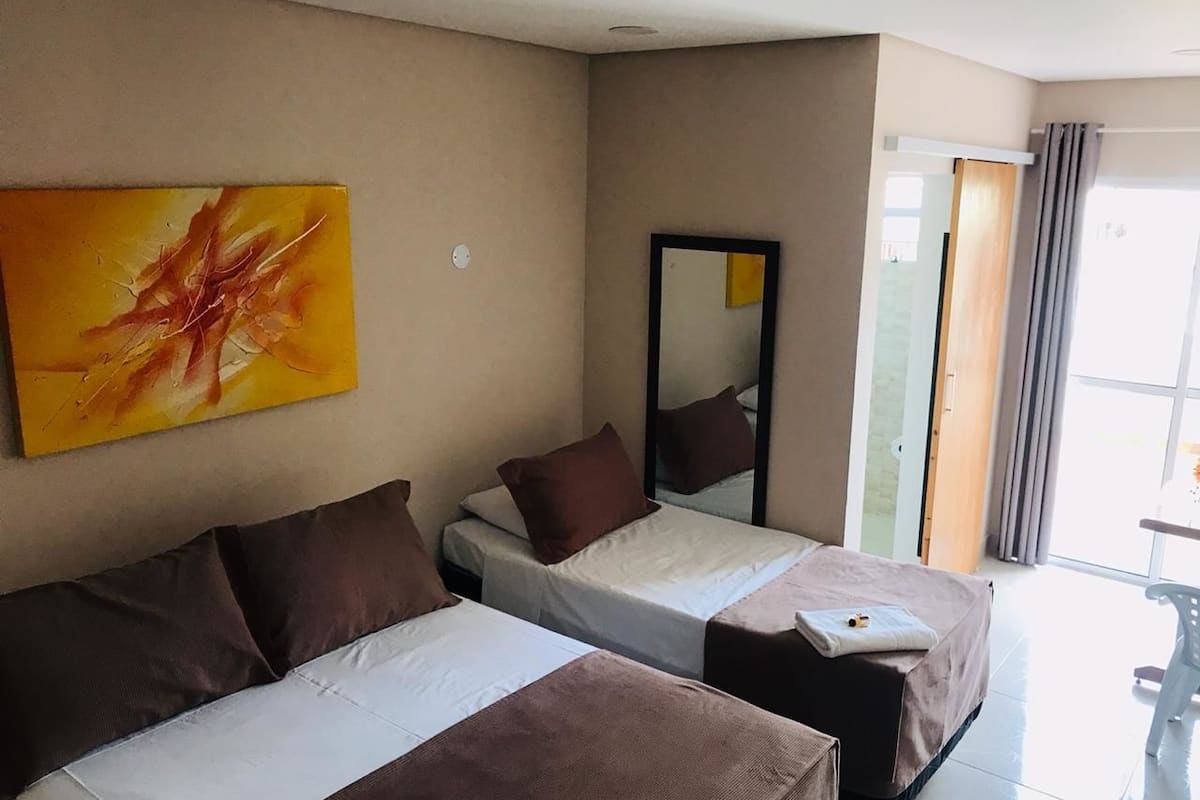 Une chambre d’hôtel avec deux lits, un grand miroir et un tableau au mur.