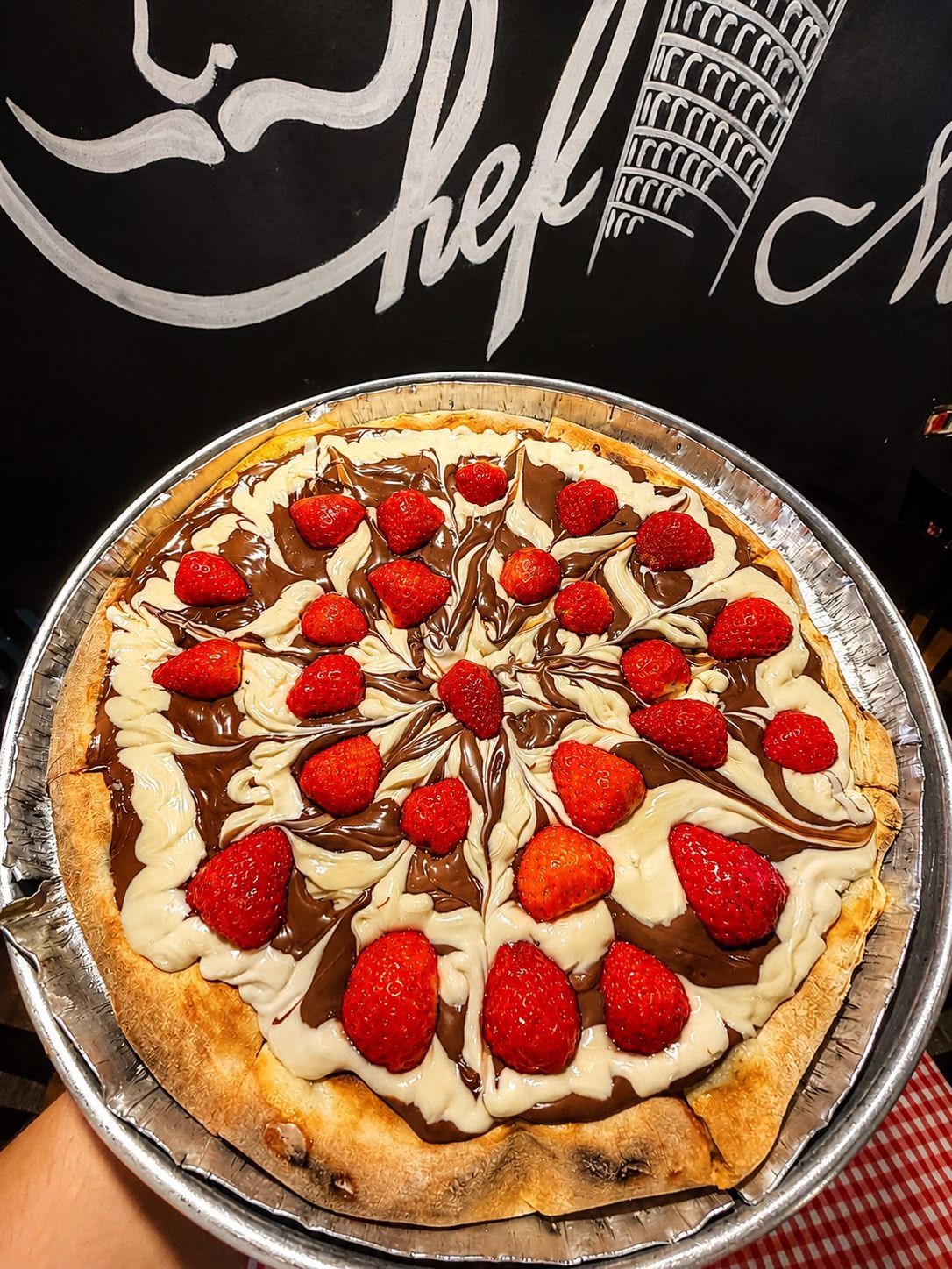 Pizza met aardbeien op een aluminium bakje.