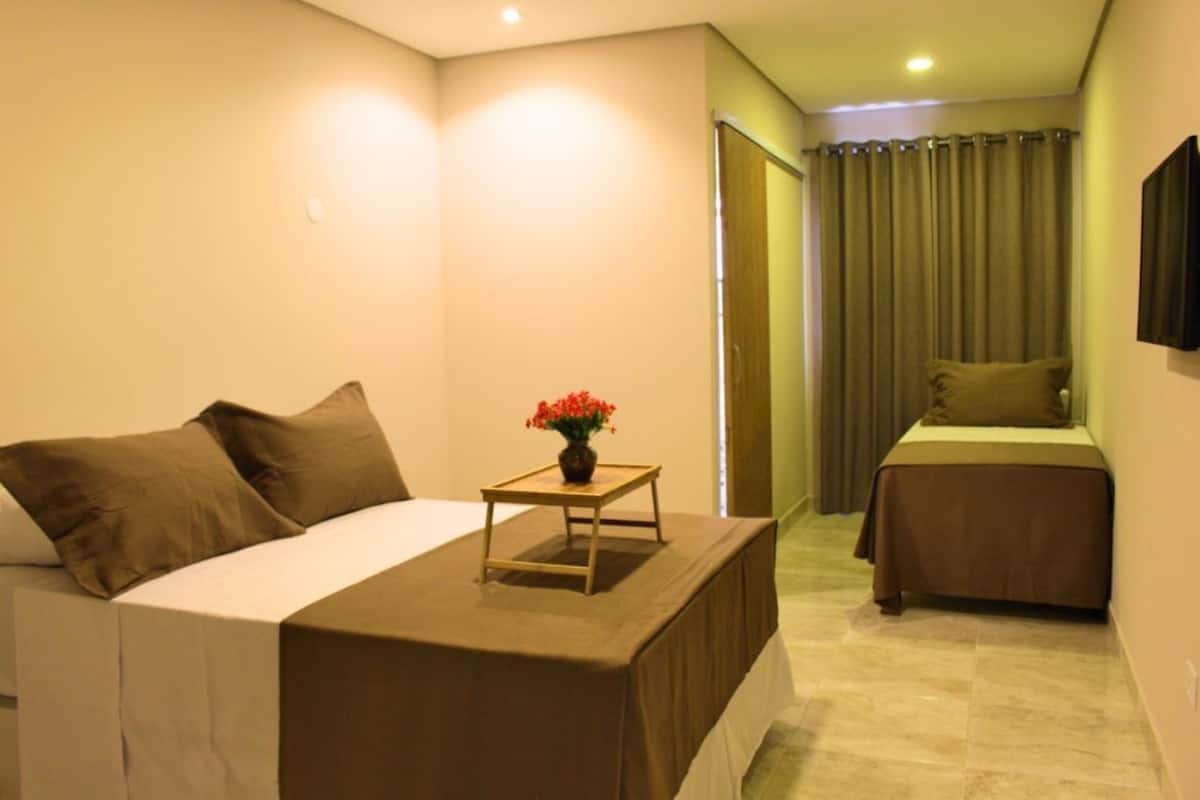 Une chambre d’hôtel avec un lit, une petite table ornée d’un vase de fleurs et un deuxième lit.