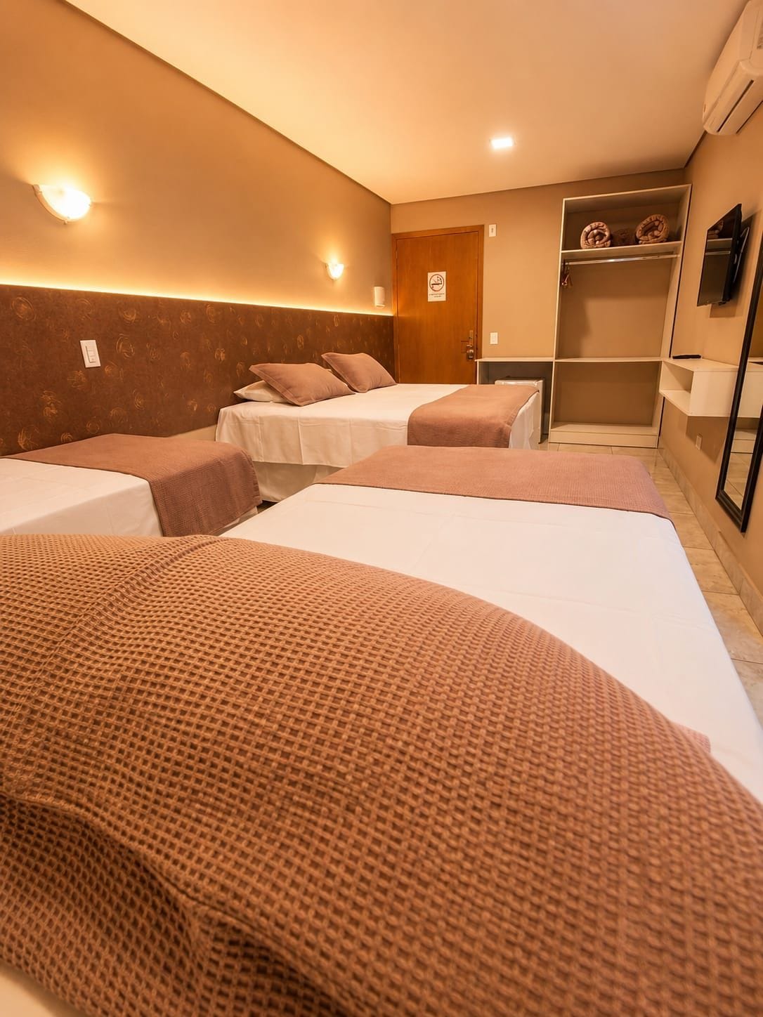 Une chambre d’hôtel avec deux lits, une armoire et un téléviseur.