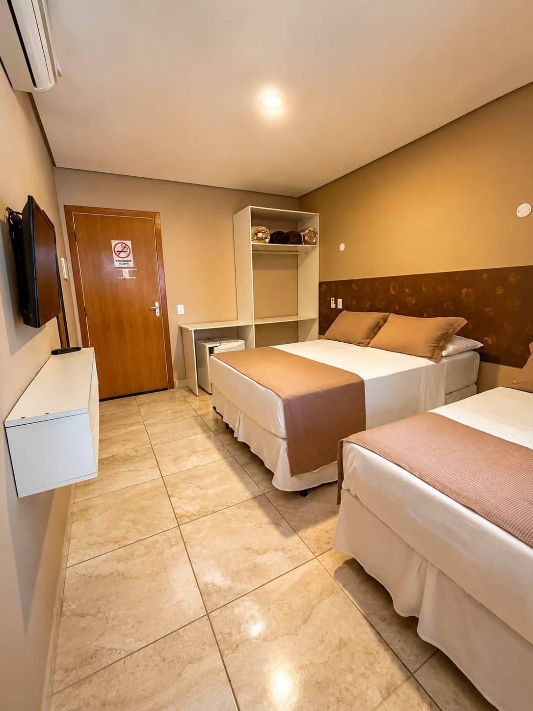 Une chambre d’hôtel avec deux lits, une armoire, un bureau et un téléviseur.