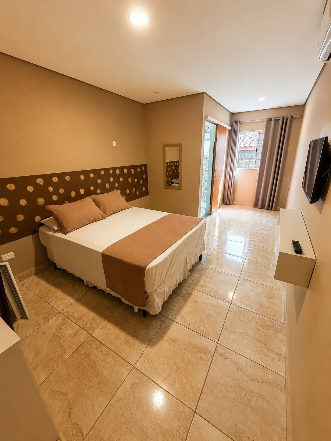 Una camera d'albergo con un letto, una televisione e un bagno.