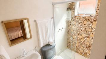 Et badeværelse med toilet, bidet, vask og bruseområde.