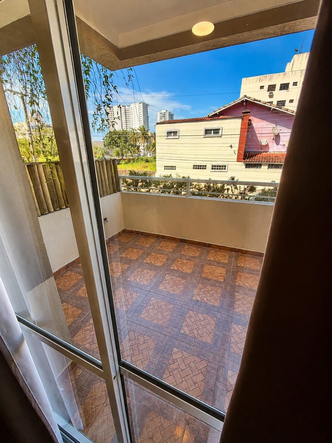 A balcony with a tiled floor and a view of buildings in the distance.