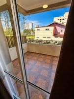 A balcony with a tiled floor and a view of buildings in the distance.