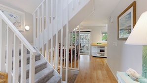 A staircase with white railings leading to a dining area with a wooden table and chairs. - Tropical Anna Maria Island Villa (Holmes Beach)
