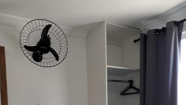 A compact room with a desk, chair, and a ceiling fan. - Hotel Lisboa (Curitiba)