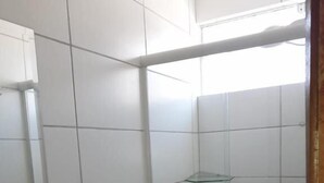 A bathroom with white tiles, a black sink, a toilet, and a glass shower enclosure. - Hotel Lisboa (Curitiba)