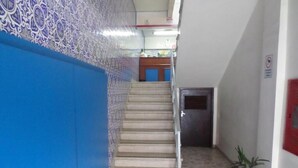 A staircase leading to a door, a blue wall with a decorative pattern, and a potted plant. - Hotel Lisboa (Curitiba)