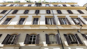 A multi-story building with arched windows and shutters, featuring a consistent architectural style. - Via del Tritone (Rome)
