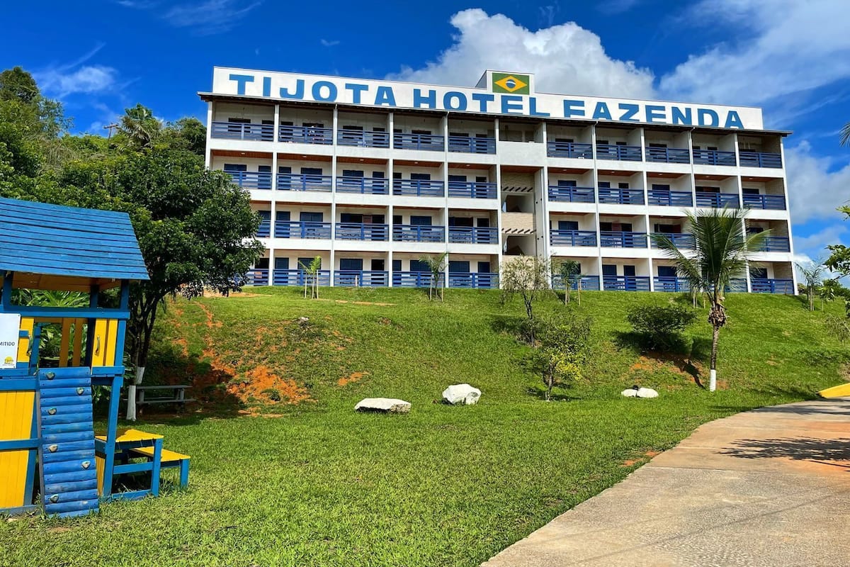 A multi-story hotel with a sign reading "TIJOTA HOTEL FAZENDA".