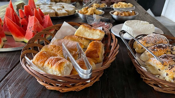 Un bufé con diferentes opciones de comida, incluyendo pan, pastelería y una presentación de sandía.