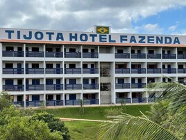 Um hotel com vários andares, varandas, céu claro e área gramada na frente.