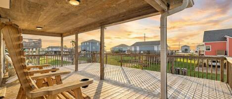 A wooden deck with a covered area and a view of houses in the background.