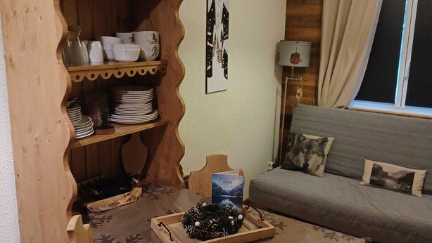 Una habitación acogedora con una mesa de madera, un sofá y una ventana con cortinas.