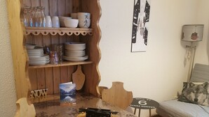 Una mesa de comedor de madera con sillas, un aparador de madera con vajilla y un cuadro en la pared.