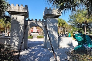 Enter through the grand stone archway, surrounded by lush greenery and a unique sculpture.