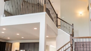 Amplio interior de vivienda de varios niveles, con cocina, comedor y escalera con barandilla de madera.