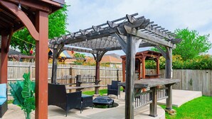 Un espacio al aire libre con patio, una pérgola, asientos y una pequeña fuente de agua.