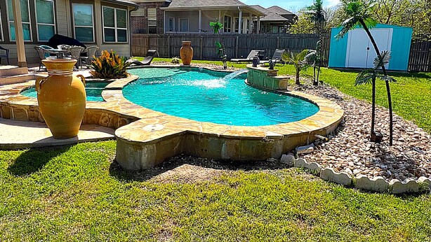 Un patio trasero con piscina, un jarrón grande y un pequeño jardín.