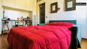 Ein Schlafzimmer mit einem großen Bett, einem Schreibtisch und einem Stuhl. An der Wand hängen gerahmte Bilder.