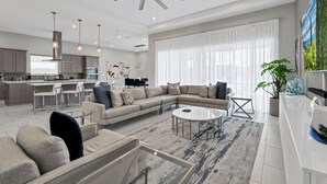 Un salon moderne avec un canapé d’angle, une table basse et un coin repas avec des chaises.