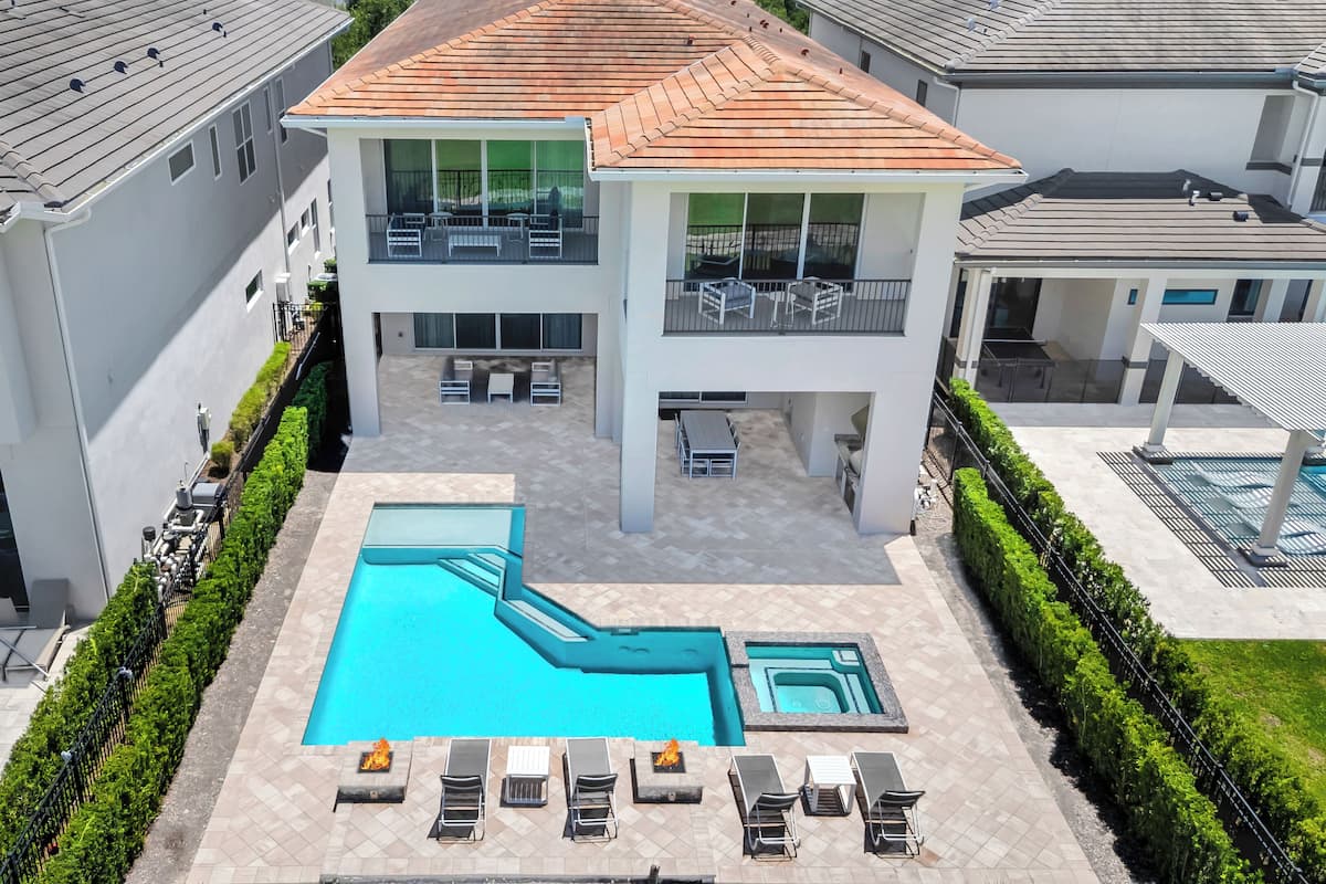 A residential building with a swimming pool, outdoor seating, and a covered patio area.