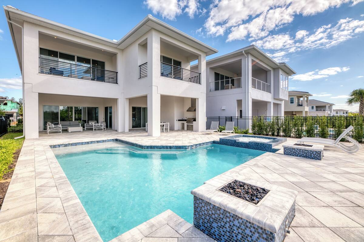 A modern two-story house with a swimming pool, outdoor seating, and a well-maintained garden.