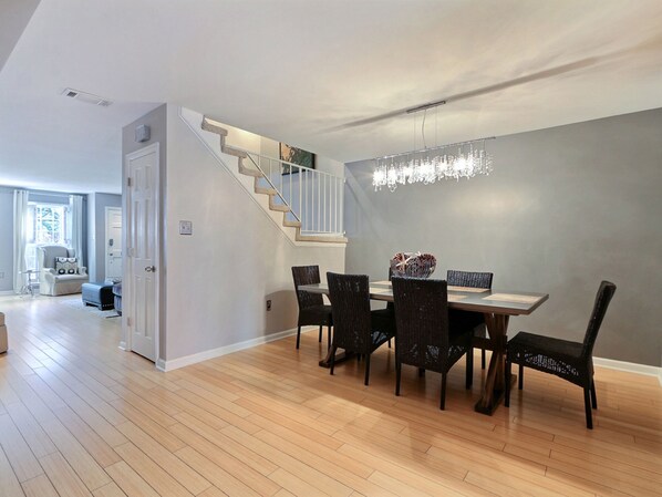 A dining area with a wooden floor, a staircase, and a chandelier. - Heated Pool Access | 5*Clean | Flex Cancelation (Savannah)