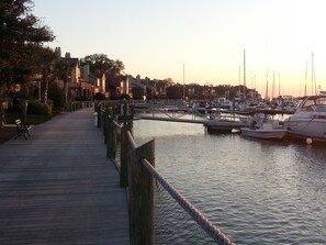 Stroll along the waterfront promenade, lined with a walkway and rope barrier, leading to a marina with docked boats.