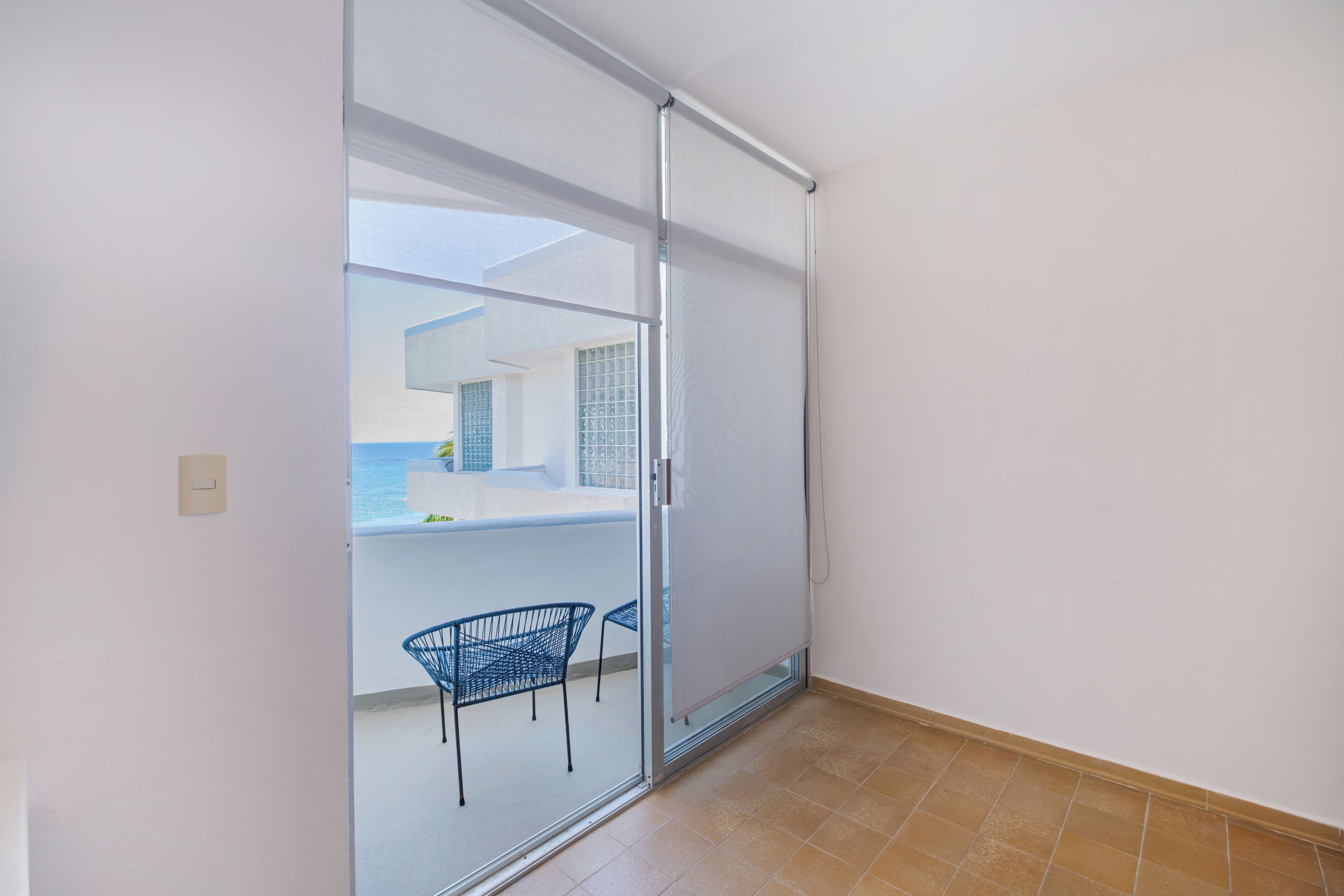 A room with a sliding glass door leading to an outdoor area with a chair and a table.