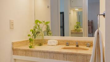 Un baño con encimera color beige, un lavabo, un espejo y un perchero para toallas.
