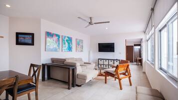 A modern living room with a sofa, chairs, a dining table, and artwork on the walls.