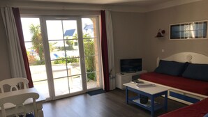 Una habitación con cama, televisor, mesa y una silla.