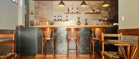 Zona de bar con sillas de madera, suelo de baldosas y lámparas colgantes.
