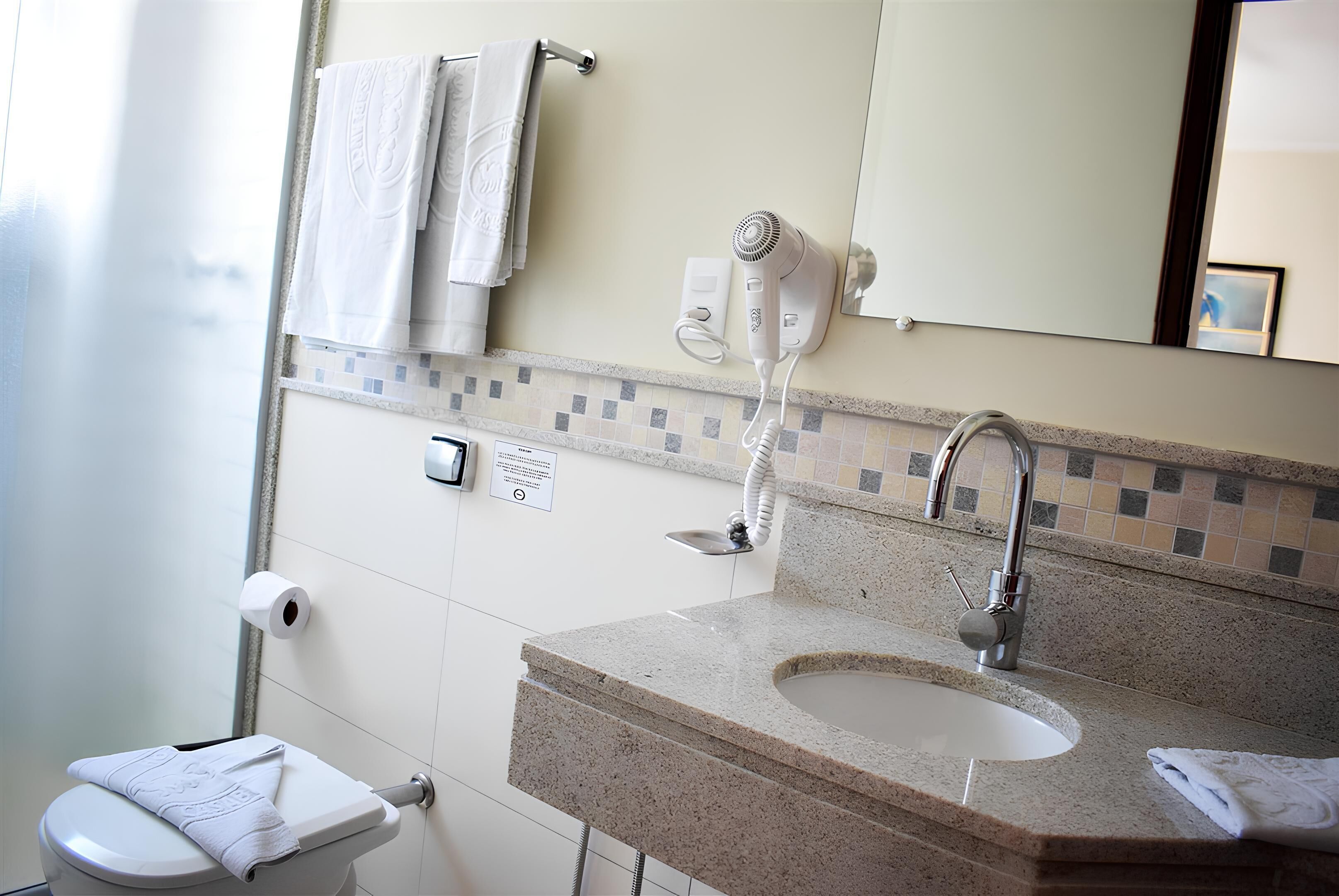 Une salle de bain équipée d’un lavabo, d’un miroir, d’un porte-serviettes et d’un sèche-cheveux.