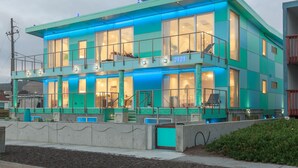 Un edificio moderno de dos pisos con ventanas amplias y un balcón.