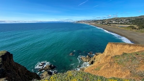 Un paisaje costero con vistas claras al océano, una playa de arena y un pueblo a lo lejos.