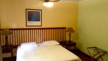 Een hotelkamer met een bed, twee bedlampen, een plafondventilator en een lijst aan de muur.